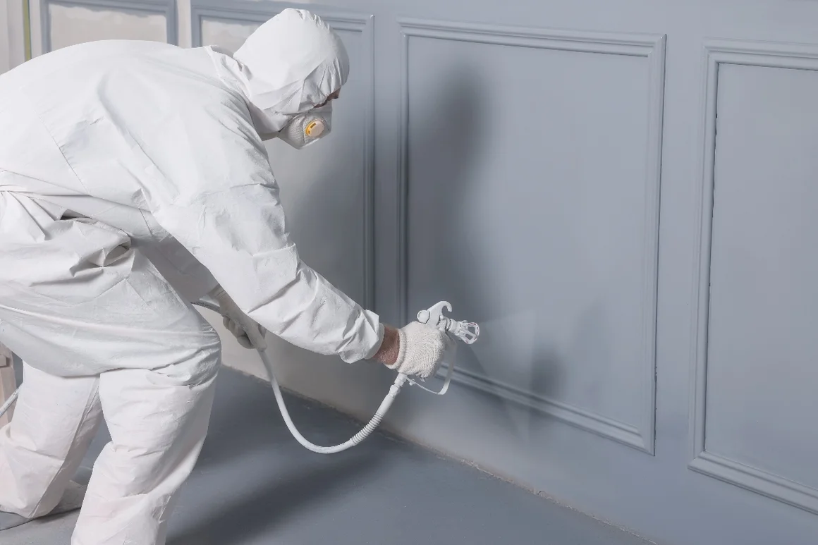 Person mit Schutzanzug und Spritzpistole